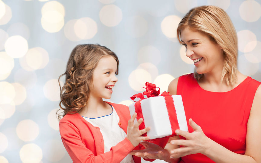 little girl handing her mom a christmas present