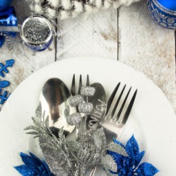 white plate and silver cutlery with blue and silver table setting decorations