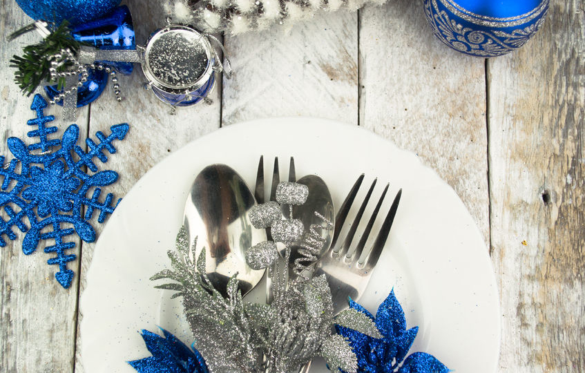 white plate and silver cutlery with blue and silver table setting decorations