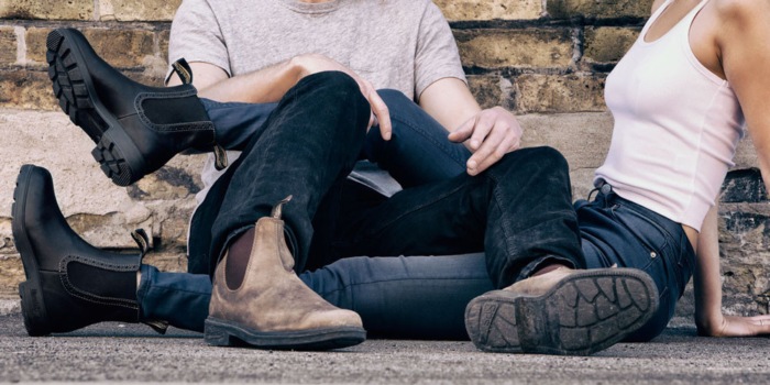 man and woman sitting on the ground wearing jeans and blundstones