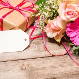 Gift wrapped on wooden table with flowers.