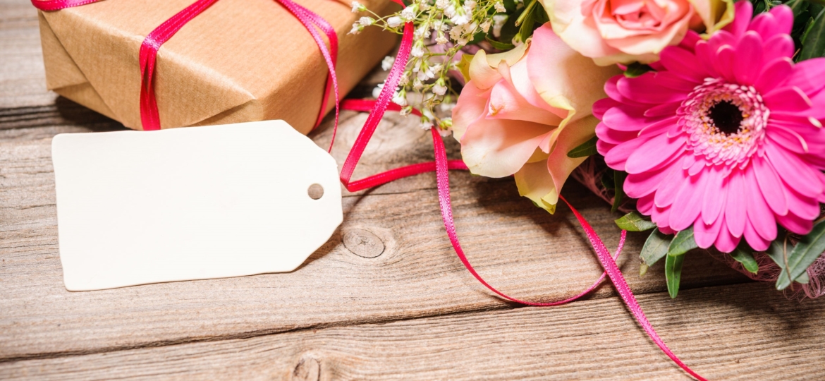 Gift wrapped on wooden table with flowers.