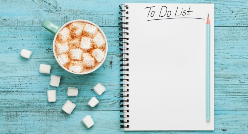 cup of hot cocoa or chocolate with marshmallow and notebook with to do list on turquoise vintage table from above, christmas planning concept. flat lay style.