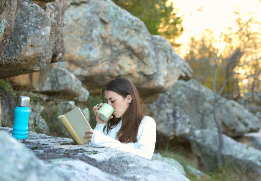 Woman drinking tea in the woods.