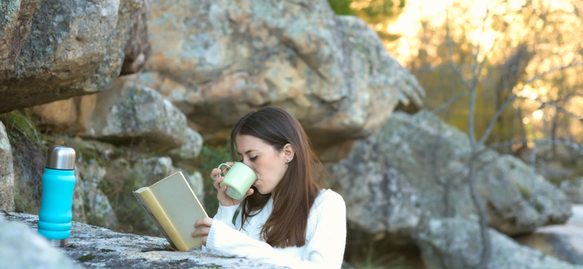 Woman drinking tea in the woods.