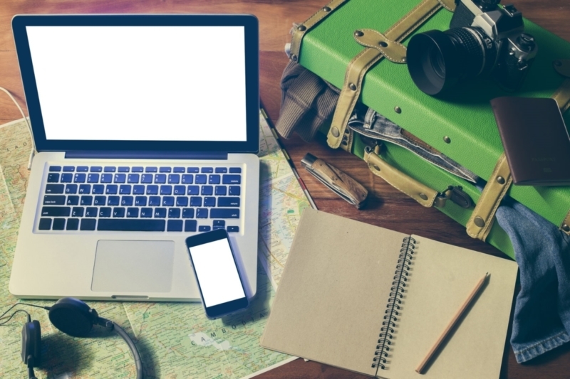 person preparing for spring break. Phone, laptop and pen and paper.