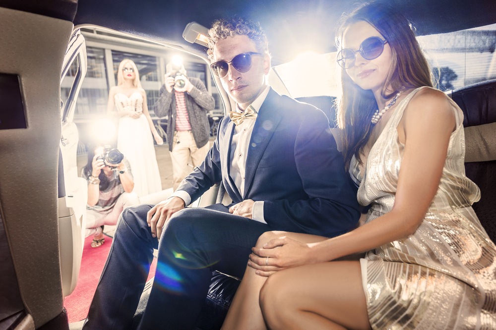 couple getting out the back of a limo with sunglasses.