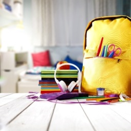 Child's room with a yellow bookbag and school supplies on the desk
