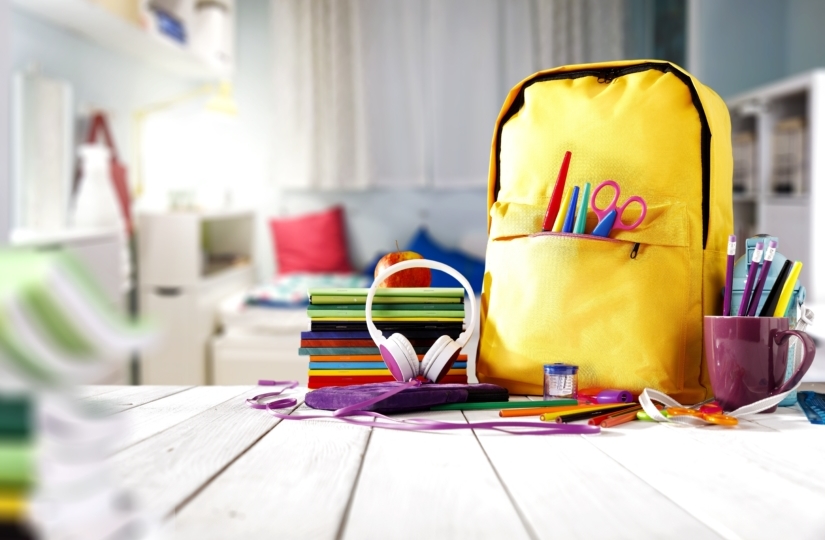 Child's room with a yellow bookbag and school supplies on the desk