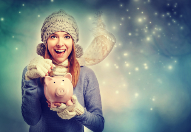 Happy young woman depositing money into her piggy bank